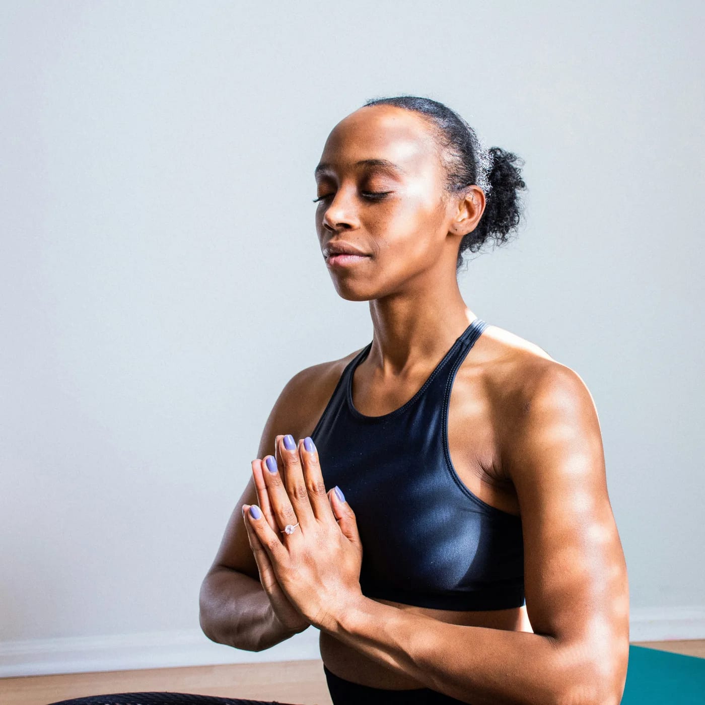 A woman sitting calmly with her eyes closed and hands together